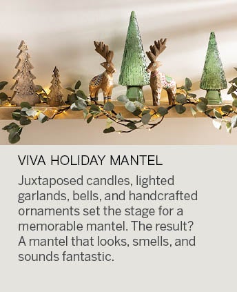 Image of a mantel decorated with wooden reindeer, glass trees and a lighted garland. VIVA HOLIDAY MANTEL: Juxtaposed candles, lighted garlands, and handcrafted ornaments set the stage for a memorable mantel. Combine something reflective, something natural, something sentimental, a pop of color, and a bell for angels. The result? A mantel that looks, smells, and sounds fantastic.