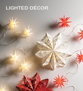 Image of a string of lighted red and white moravian stars and large cut paper stars. Shop Lighted Décor.