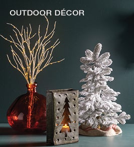 Image of lighted birch branches, metal votive lanterns and a flocked pine tree. Shop outdoor décor.