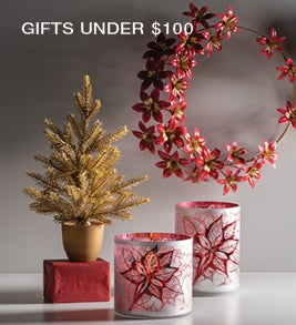Image of a metal holiday wreath, hurricane candles and a small faux pine tree. Shop Gifts Under $100.