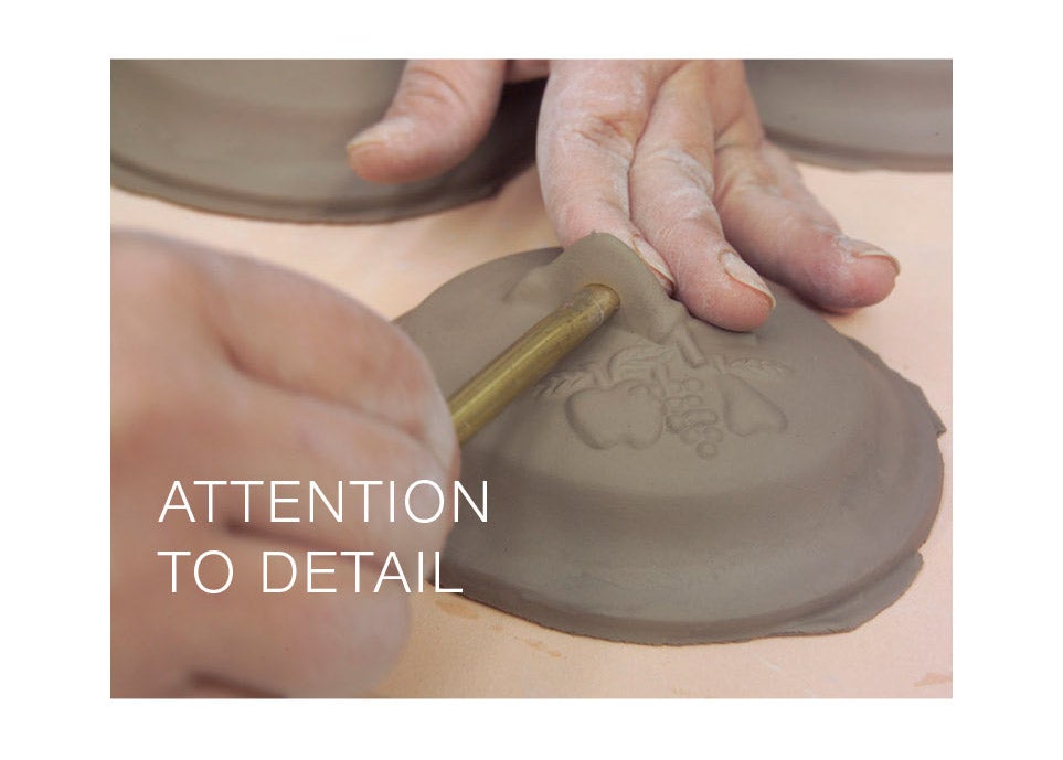 artisan adding detail to pot cover - attention to detail